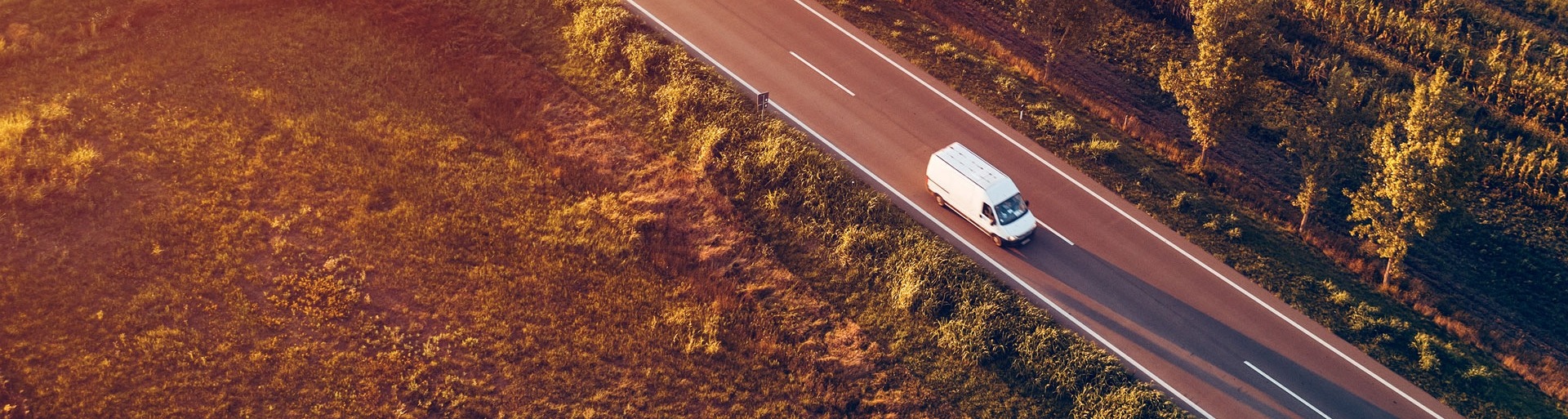 Luchtfoto van bestelwagen op de weg in de zomerzonsondergang